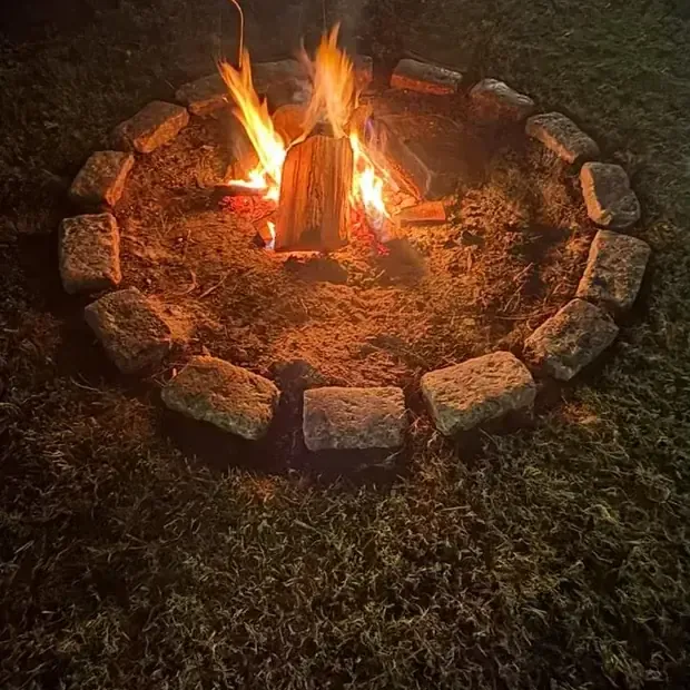 Un fogón encendido de noche, en ronda de piedras.
